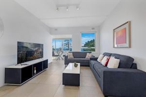 a living room with two couches and a tv at Ocean View 1 bedroom Private Apartment next to Maroubra Beach in Sydney