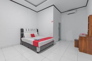 Un dormitorio con una cama en una habitación blanca. en RedDoorz @ Geopark Ciletuh Sukabumi, en Cilowa