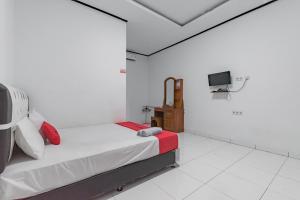 a white room with a bed and a tv at RedDoorz @ Geopark Ciletuh Sukabumi in Cilowa