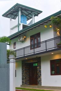 a white house with a balcony on top of it at Monkey Island Hotel in Hikkaduwa