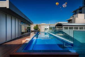 a swimming pool on a building with hot air balloons in the sky at Adele Apartment Hotel East Melbourne in Melbourne