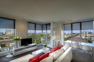 a living room with a white couch and large windows at Adele Apartment Hotel East Melbourne in Melbourne