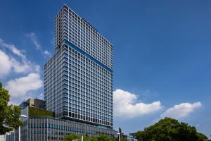 wysoki szklany budynek z niebieskim niebem w obiekcie The Royal Park Hotel Iconic Nagoya w mieście Nagoja