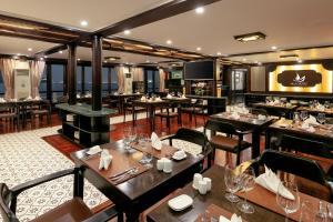 un restaurante con mesas y sillas y un bar en Mila Cruises en Ha Long