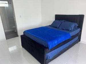 a bed with blue sheets and blue pillows on it at Cabañas JUDÁ in Yopal