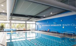 een groot zwembad met een blauwe muur bij The Retreat Inverloch in Inverloch