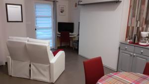 ein Wohnzimmer mit einem weißen Stuhl und einem Tisch in der Unterkunft l'annexe du jardin in Saint-Doulchard
