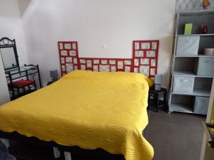 ein Schlafzimmer mit einem Bett mit gelber Tagesdecke in der Unterkunft l'annexe du jardin in Saint-Doulchard