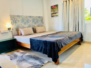 a bedroom with a bed with a blue blanket and a window at Bhūma in Havelock Island