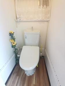 a white toilet in a small bathroom with wooden floors at grori house in Musashino