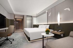 um quarto de hotel com uma cama branca e uma secretária em Crowne Plaza Jinan Runhua em Jinan