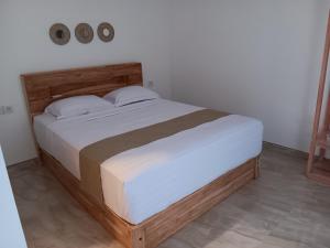 a bedroom with a large bed with a wooden headboard at Manuh Guest House in Nusa Dua