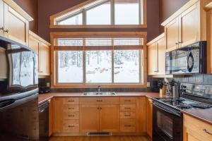 cocina con armarios de madera, ventana y fregadero en Eagle Ridge Pet-Friendly Chalet, en Big White