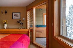 Un dormitorio con una cama y una ventana y una bañera. en Eagle Ridge Pet-Friendly Chalet, en Big White