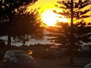 una puesta de sol con coches estacionados en un estacionamiento en Surfside Sunset, en Safety Bay