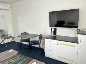 a room with a table and a flat screen tv at Otway Gate Motel in Colac