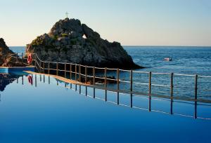 a swimming pool next to the ocean with an island at UNA HOTELS Capotaormina in Taormina