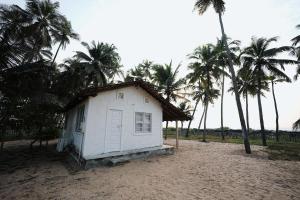 a small white house on the beach with palm trees at GB Beach house in Udupi