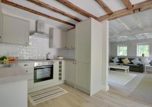 a kitchen with white cabinets and a living room at Middle Barn in Leigh