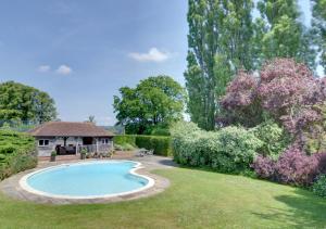 um jardim com uma piscina e um gazebo em Middle Barn em Leigh