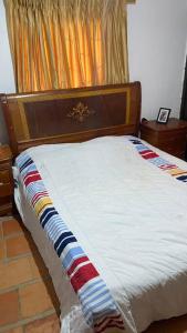 1 cama con cabecero de madera y colcha blanca en Cabaña 6 personas zonas verdes., en Los Santos