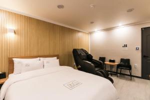 a hotel room with a bed and two chairs at Hotel The City in Gwangju