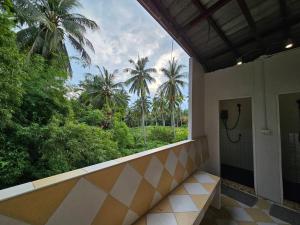 a bathroom with a view of palm trees from a balcony at Hao Norn Hostel in Thongsala