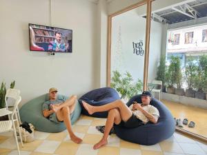 two people laying on bean bags in a room at Hao Norn Hostel in Thongsala