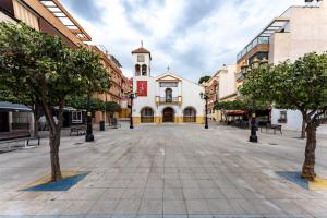 an empty street in a city with a clock tower at Plaza De la Iglesia in Rincón de la Victoria