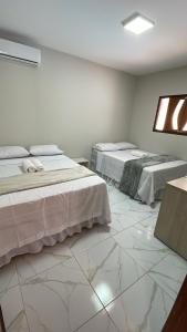 two beds in a room with white marble floors at Casa de Férias á 400m pra Praia de Cabo Branco in João Pessoa