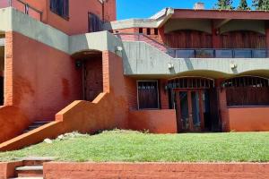 a red building with a staircase and a door at Casa en Villa Carlos Paz in Villa Carlos Paz