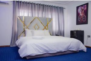 a bedroom with a large bed with white sheets and pillows at Dee Rocket in Ibadan