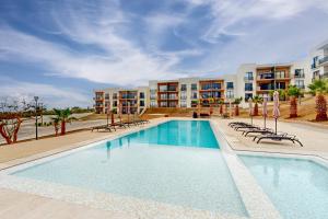 una gran piscina con sillas y apartamentos en condominio en Maralta D 102 en Cabo San Lucas