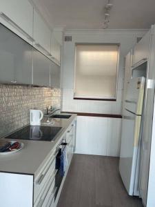 a white kitchen with a sink and a refrigerator at Ocean View 1 bedroom Private Apartment Near Maroubra Beach in Sydney