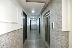 un couloir d'un bâtiment avec portes noires et sols en béton dans l'établissement FabHotel Belwood, à New Delhi