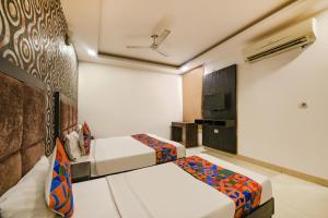 Cette chambre comprend 2 lits et une télévision. dans l'établissement FabHotel Belwood, à New Delhi