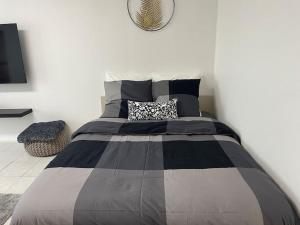 um quarto com uma cama com um edredão preto e cinzento em Appartement Cosy proche Paris em Le Bourget