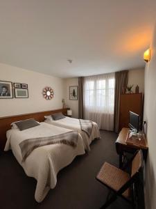 een hotelkamer met 2 bedden en een bureau met een laptop bij Le Téméraire Hôtel in Charolles