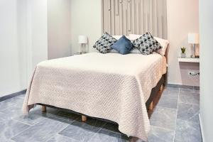 a bed with a white blanket and pillows on it at Departamento Marloma #1 in Ensenada