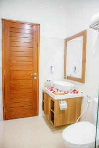 une salle de bain avec un lavabo, des toilettes et un miroir dans l'établissement Shanta Villa, à anur