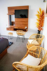 a bedroom with wicker chairs and a flat screen tv at Shanta Villa in Sanur