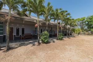 a row of palm trees in front of a building at RedDoorz near Pantai Ujung Genteng in Cijaringao