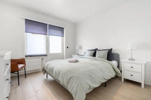 una camera bianca con un grande letto e una sedia di Sunny Apartment 500m from the beach Oostend a Ostenda