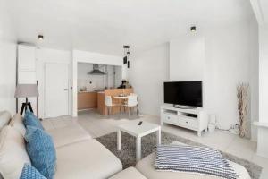 un soggiorno con divano bianco e TV di Sunny Apartment 500m from the beach Oostend a Ostenda