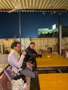 zwei Männer sitzen an einem Tisch mit einem Glas Wein in der Unterkunft Hotel Hashim in Jaisalmer