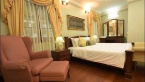 1 dormitorio con 1 cama blanca y 1 silla en CASA ANDALUSIA, en Alor Setar