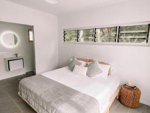 een slaapkamer met een bed met witte lakens en 2 ramen bij M Resort & Spa in Port Vila