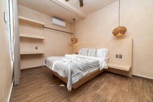 a bedroom with a bed with white sheets and wooden floors at The Teodoro in Tulum