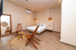 a bedroom with a bed and two chairs and a mirror at The Teodoro in Tulum