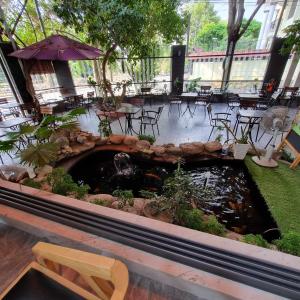 a patio with a pond and tables and chairs and an umbrella at Homestay Thule in Ho Chi Minh City